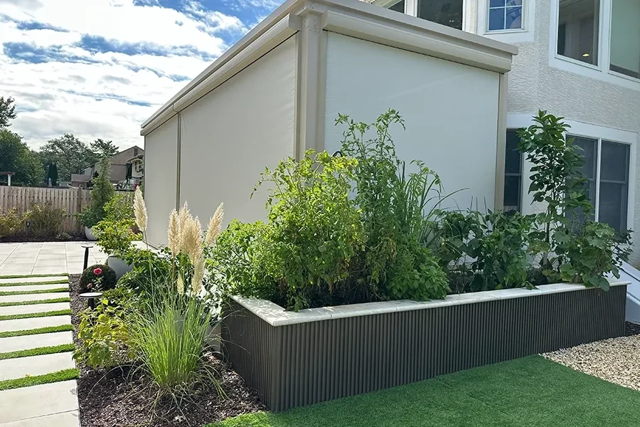 Raised planting bed beside a home and paved path